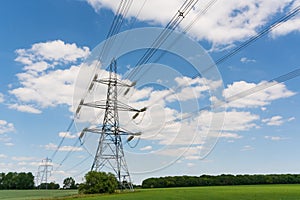 Electricity pylons in a field with blue sky.