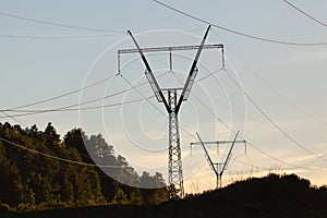 Electricity pylons, power lines and trees silhouetted against a