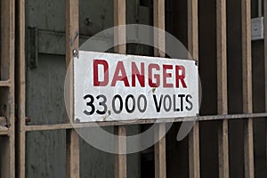 Electricity safety danger sign on a locked metal gate