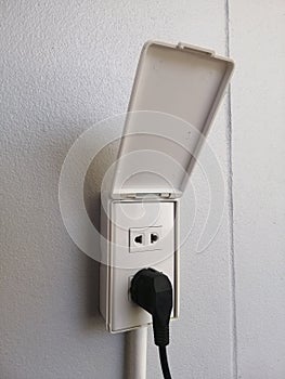 Electricity socket installed on white concrete wall, light switch on the wall