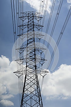 Electricity transmission lines and pylon silhouetted against blue sky and cloud,high voltage tower