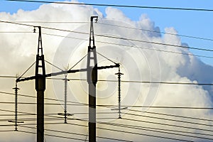 Electricity transmission power lines against white clouds. High