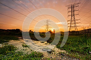Electricity transmission pylon silhouetted against blue/ Orange sky at dusk.