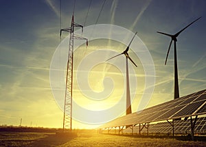 Electricity transmission pylon with solar panels and wind turbines