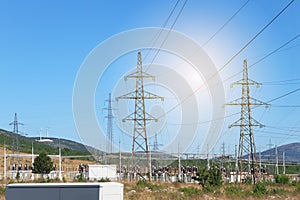 Electricity transmission pylons against blue sky. High voltage electricity poles with wind turbines