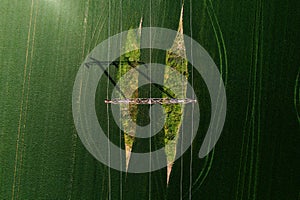 Electricity transmission tower and power line in agricultural field, top view from drone pov