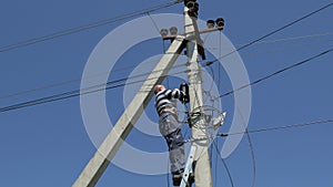 Electricity work, man repairs electric pole wearing all the safety equipment