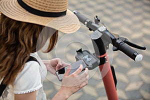 Electro-mobility. Traveler unlocking an e-scooter on the street. Traveler exploring old town on environmentally friendly