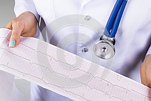 Electrocardiogram, ecg in hand of a female doctor. Medical health care. Clinic cardiology heart rhythm and pulse test closeup.