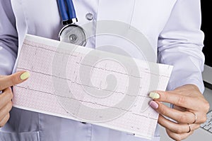 Electrocardiogram, ecg in hand of a female doctor. Medical health care. Clinic cardiology heart rhythm and pulse test closeup.