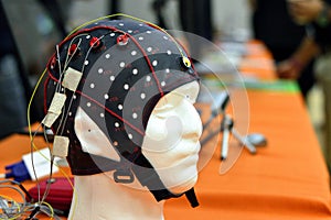 The electroencephalogram EEG head cap with flat metal discs electrodes attached to a white plastic modelâ€™s head