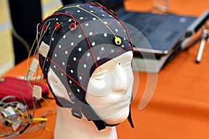 The electroencephalogram EEG head cap with flat metal discs electrodes attached to a white plastic modelâ€™s head
