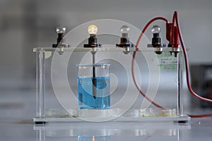 Electrolyte solution turns on a light bulb. Experiment in the chemistry laboratory