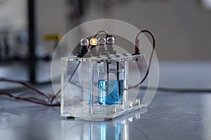 Electrolyte solution turns on a light bulb. Experiment in the chemistry laboratory