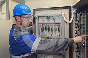 Electromechanic in electrical safety gloves holds power cable, cabling connection of high voltage power electric line in
