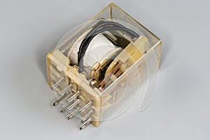Electromechanical coil relay in transparent dust cover on gray background