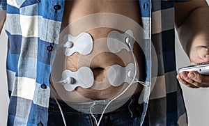 Electronic apunctuator on the abdomen of a man. Treatment and relaxation of the abdominal muscles. Home physiotherapy