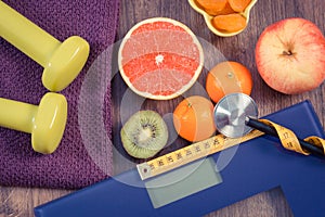 Electronic bathroom scale, centimeter and stethoscope, fresh fruits, dumbbells for fitness, slimming and healthy lifestyles