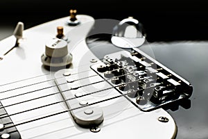 Electronic black and white guitar body close up with strings, volume and tone controls. Music background