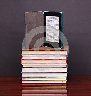 Electronic book reader and pile old books on wood desk