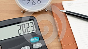 Electronic calculator with 2023 on background with clock and diary. New year business concept