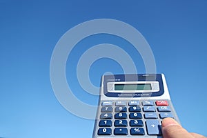 Electronic calculator and the hand in the blue sky