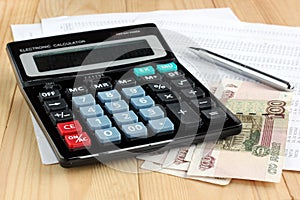 Electronic calculator, pen and Russian money on sheets of paper