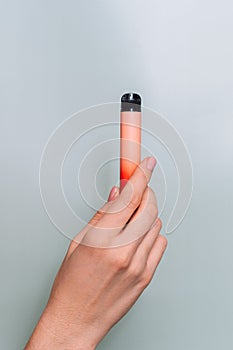 Electronic cigarette in female hand against green background