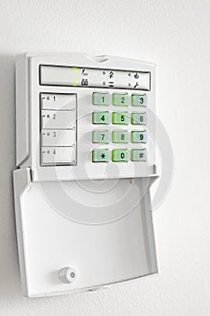 Electronic control panel of the apartment and office security alarm system with electronic keypad on a white wall