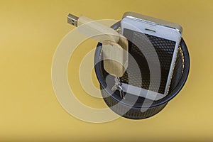 Electronic equipments in trash can on yellow background