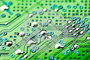 Electronic green printed circuit board with soldered copper contacts, holes, close-up, selective focus