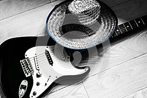 Electronic guitar and cowboy hat on wooden floor. Black and white photo