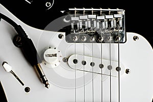 Electronic guitar details close up and wire cable jack. Close up black and white electronic guitar.