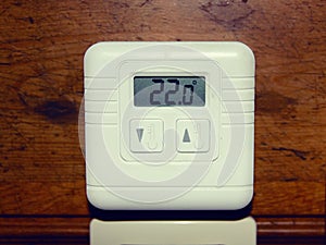 Electronic heating temperature controller, mounted on the wall of a wooden house
