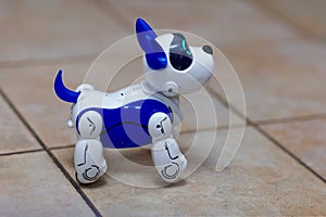 Electronic interactive toy dog puppy on a beige ceramic floor background of selective focus. High technology concept, pet of the f