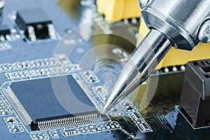 Electronic manufacturing and repair concept - close up shot of soldering iron in a process of fixing microcircuit