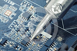 Electronic manufacturing and repair concept - close up studio shot of soldering iron in a process of fixing microcircuit