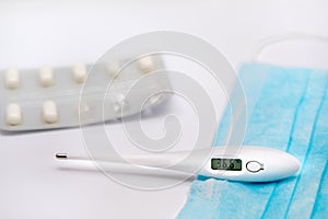 Electronic medical thermometer showing the temperature of 36.6 C lies on a blue medical protective bandage