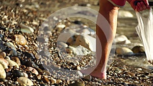 An electronic metal detector on the pebble beach. A man is looking for the luxuries lost by tourists in water and on the