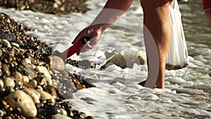 An electronic metal detector on the pebble beach. A man is looking for the luxuries lost by tourists in water and on the