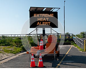 Electronic mobile sign that says Excessive Heat Alert. The sign is on a deserted street by the entrance to the boardwalk by the