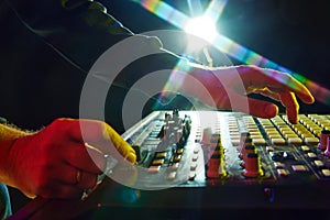 Electronic music, party and night club entertainment. Close-up of dj mixer, man adjusting sounds and beats on dark