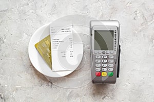 Electronic payments in restaurant. Bank card near aquiring terminal and bill on grey background top view