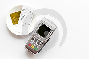 Electronic payments in restaurant. Bank card near aquiring terminal and bill on white background top view copy space
