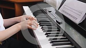 Electronic piano. Children`s hands on a keyboard instrument. Side view.