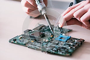 Electronic repair engineer soldering motherboard