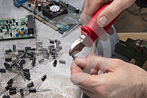 An electronic service worker cuts the tip of the capacitor with a pliers.