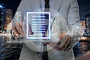 Electronic signature concept. Double exposure of businessman with tablet and night cityscape