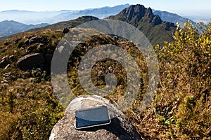 Electronic tablet over a rock in a mountain landscape