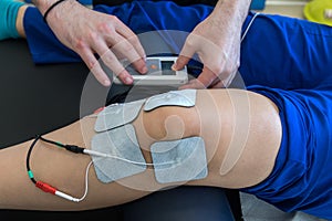 Electronic therapy on knee used to treat pain.